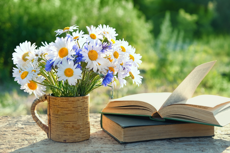 Blumenstrauss steht in Tasche, neben Büchern