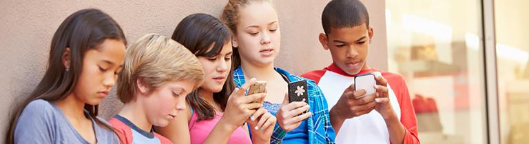 Eine Gruppe von Kindern sind auf ihre Smartphones konzentriert.