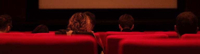 Blick auf eine Kinoleinwand mit Publikum in den Sitzen
