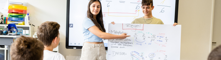 Sekundarschülerin und -schüler präsentieren ein Plakat