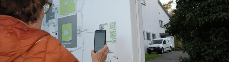 Eine Besucherin scannt den QR-Code zum digitalen Wegweiser auf Mariaberg