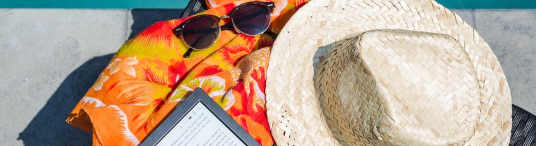 Ein Strandtuch, ein E-Reader, eine Sonnenbrille und ein Strohhut liegen neben einem Pool.