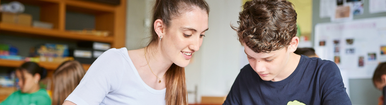 Studentin der PHSG erklärt einem Schüler eine Aufgabe 