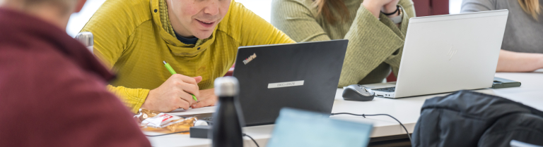 Lehrperson und Lernende schauen auf Bildschirm und reden darüber