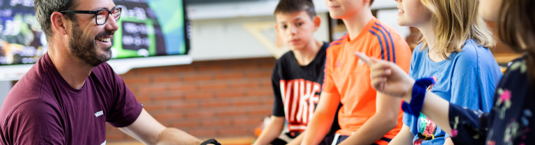 LP sitzend und redet mit Schüler