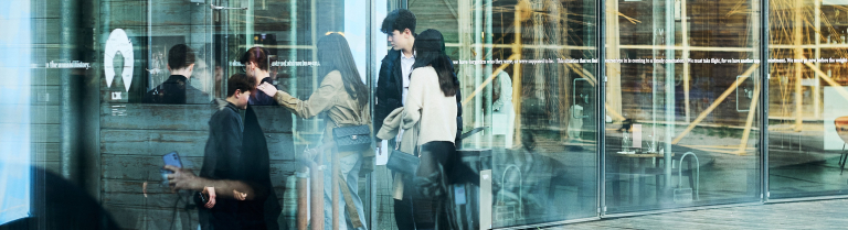 Mehrere Jugendliche gehen durch eine Glastür