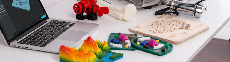 Laptop und 3D-Drucker mit bunten gedruckten Gegenständen