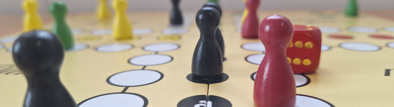 Spielfiguren und Würfel stehen auf einem Spielbrett
