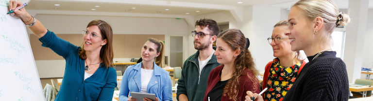 Dozentin zeigt den Student:innen etwas am Flipchart
