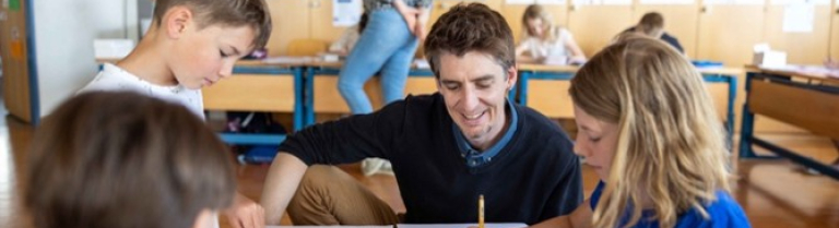 Fachperson ist mit Schülern um einen Tisch