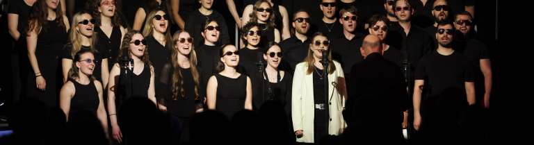 Ein Chor singt auf einer dunklen Bühne