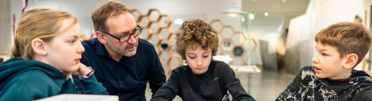 Lehrperson mit 3 Schüler:innen beim Erarbeiten