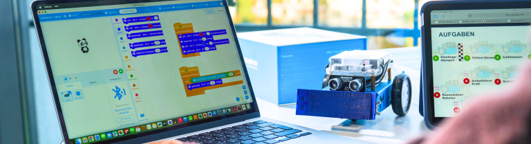 Person programmiert an Laptop einen Roboter