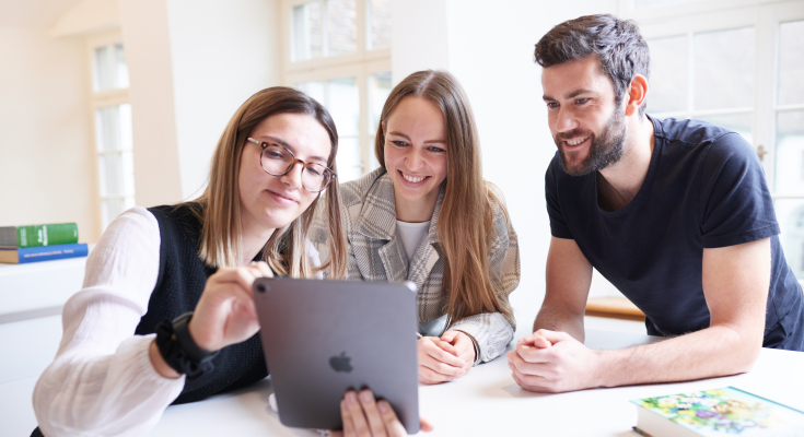 Studierende betrachten gemeinsam ein tablet