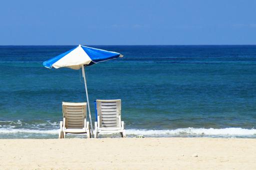 Zwei Liegestühle und ein Sonnenschirm am Strand