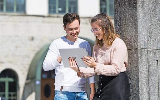 Zwei Studierende mit Laptop im Gespräch