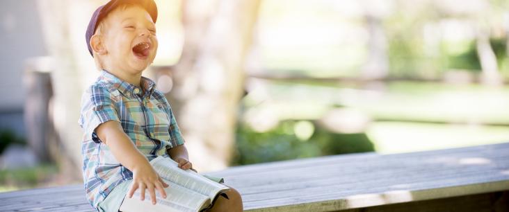 Kind lacht mit Buch in der Hand