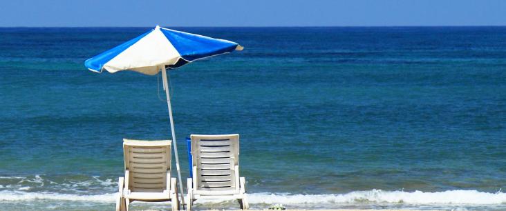 Zwei Liegestühle und ein Sonnenschirm am Strand