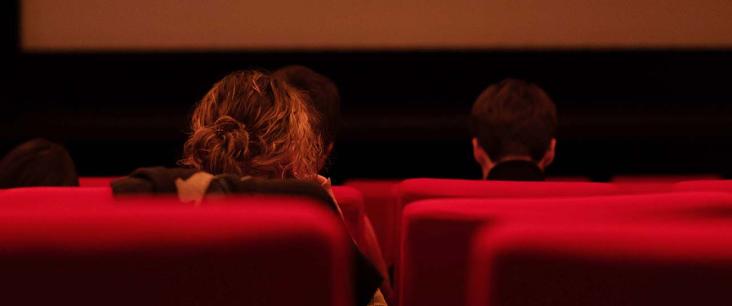 Blick auf eine Kinoleinwand mit Publikum in den Sitzen