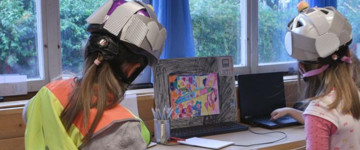 Zwei Mädchen mit Warnweste und Helm auf dem Kopf spielen Roboter im Kindergarten
