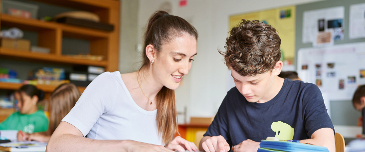 Studentin der PHSG erklärt einem Schüler eine Aufgabe 