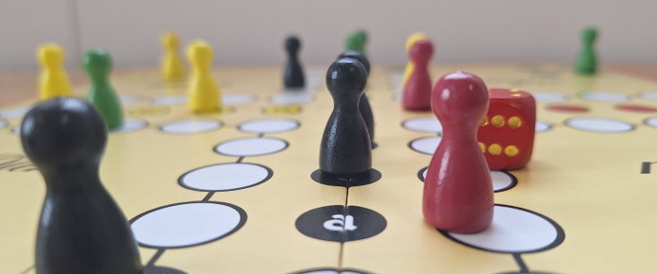 Spielfiguren und Würfel stehen auf einem Spielbrett