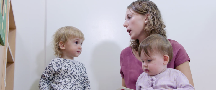 Fachperson spricht mit einem Kinder über ein Bilderbuch