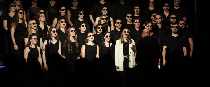 Ein Chor singt auf einer dunklen Bühne