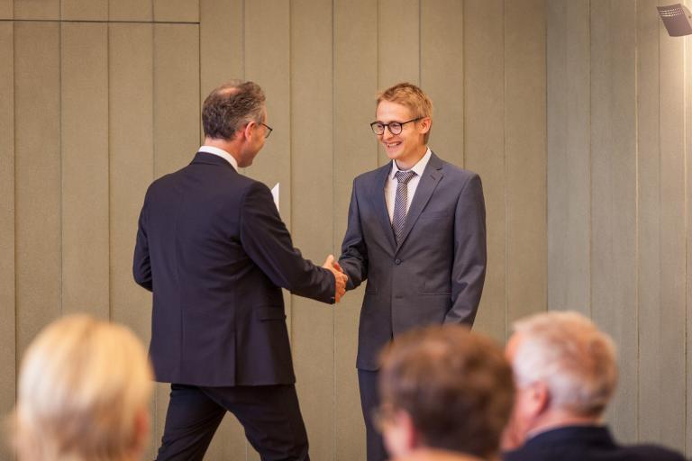 Rektor Horst Biedermann gratuliert Absolvet zum Diplom