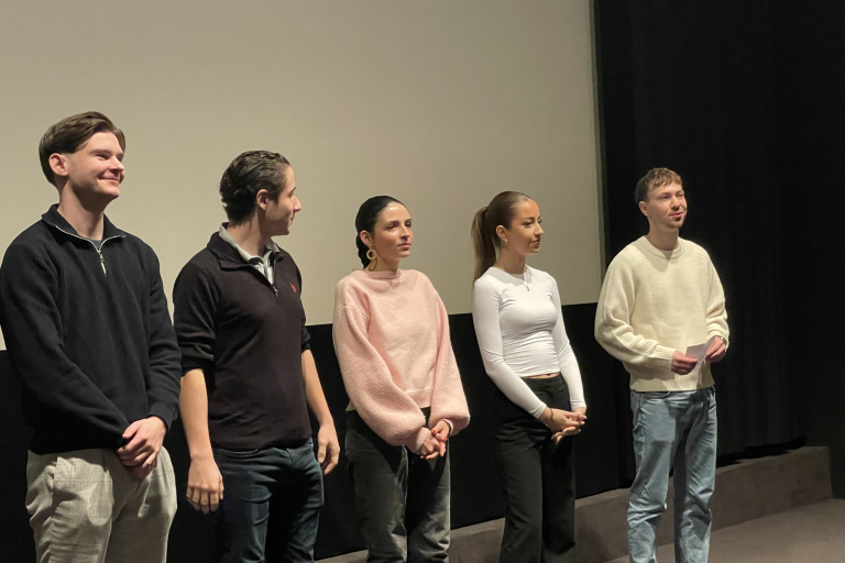 Mehrere Personen stehen auf der Kinobühne vor der Leinwand