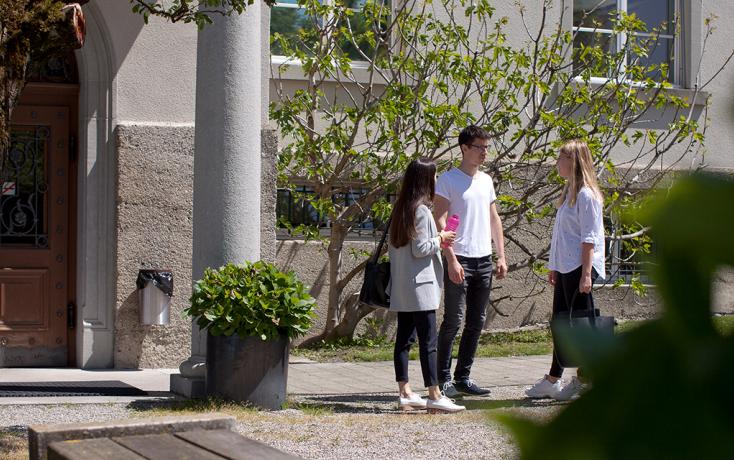 Drei Studierende stehen vor einem PHSG-Gebäude und unterhalten sich