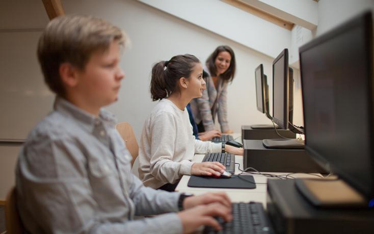 Zwei Jugendliche am Computer mit Lehrerin