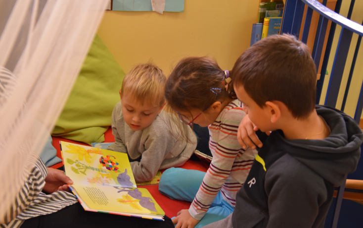 Drei Kinder betrachten ein Bilderbuch