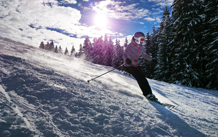 Ein junges Mädchen fährt mit Skiern einen verschneiten Hügel hinunter