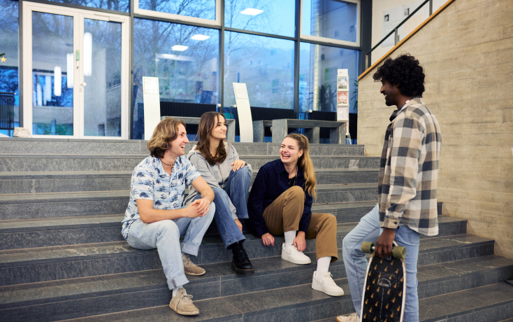 Vier Studierende im Pausengespräch auf einer Treppe