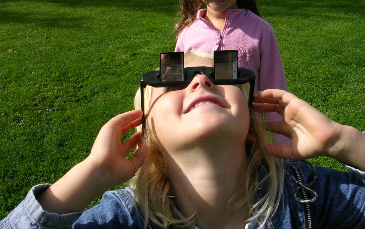 Frau mit Vergrösserungsbrille schaut zum Himmel