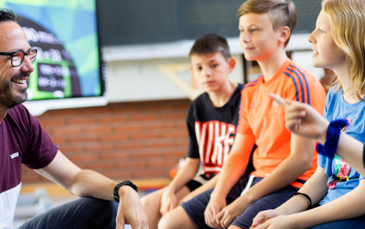 LP sitzend und redet mit Schüler