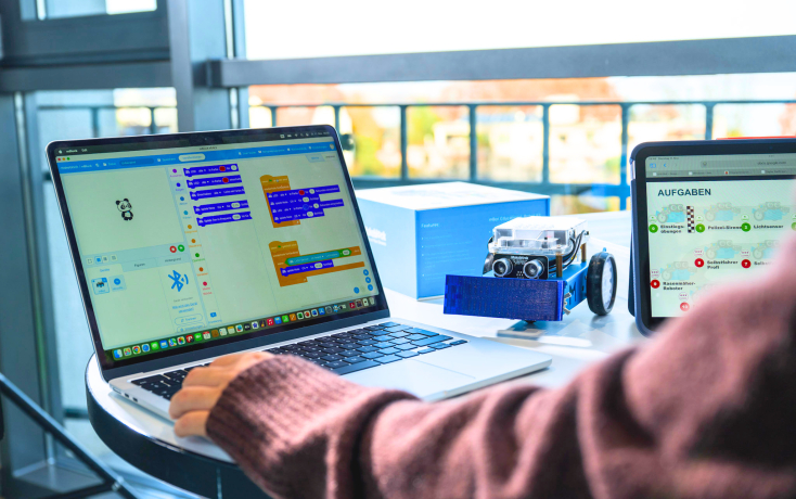Person programmiert an Laptop einen Roboter