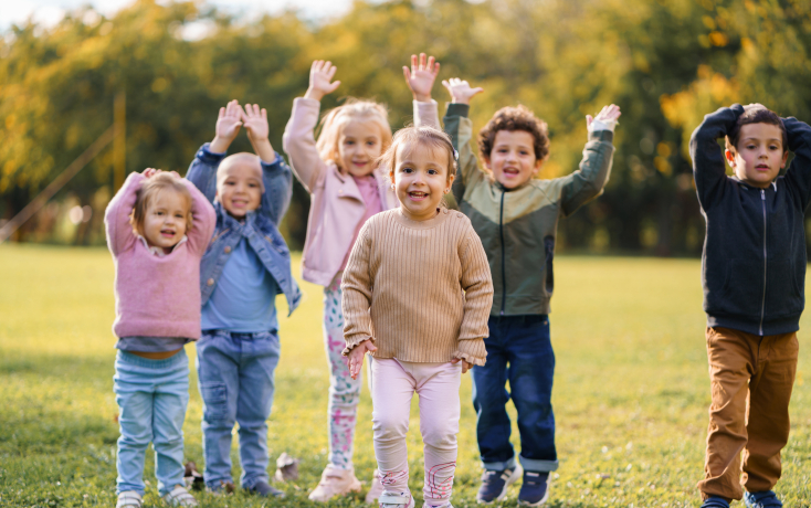 eine Gruppe Kinder bewegt die Arme im Freien
