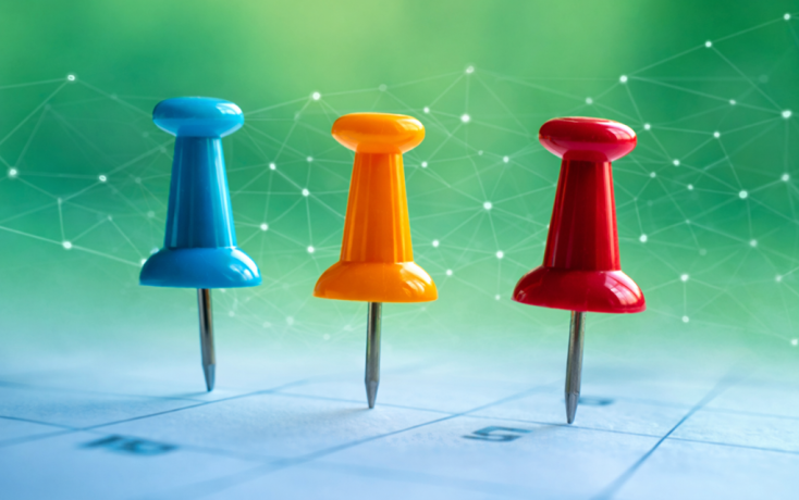 Drei bunte Pins auf einem Kalender als Symbol für aktuelle KI-News und Veranstaltungen des IDIB