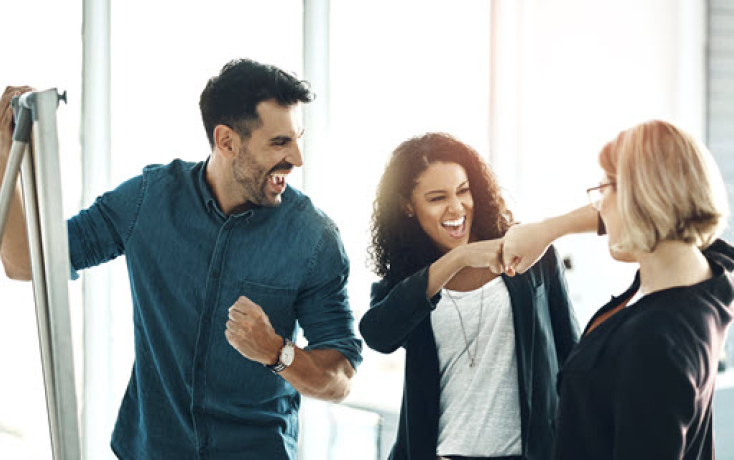 Drei Personen feiern gemeinsam einen Erfolg als Symbol für begleitete Schulentwicklung