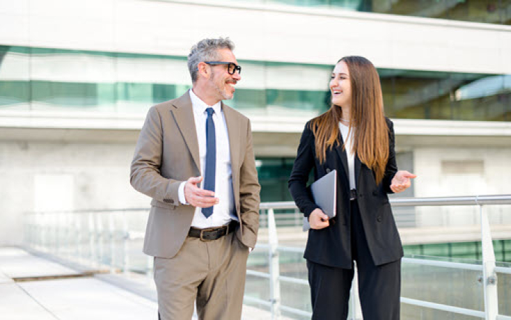 Zwei Führungspersonen im Gespräch vor einem modernen Gebäude als Symbol für KI-Leadership im Bildungsbereich