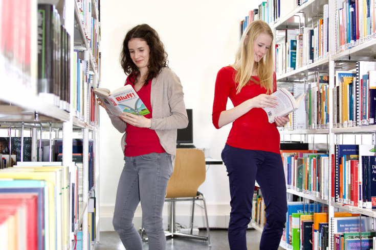 Zwei Frauen betrachten Bücher in Bibliothek