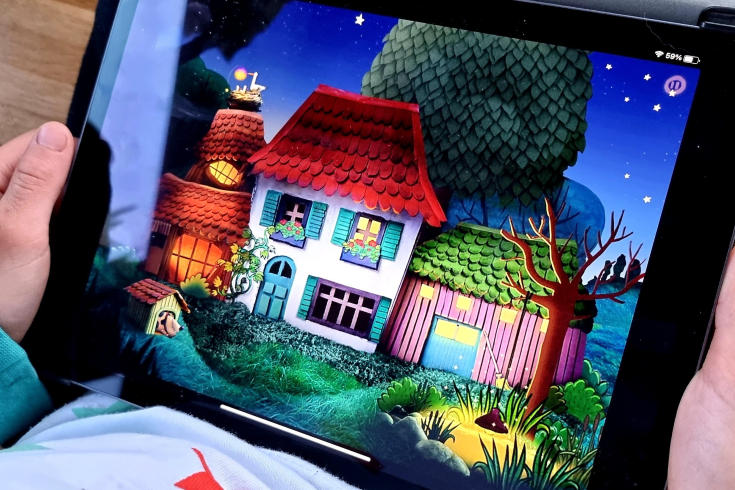 Kind betrachtet ein Geschichtenhaus und Garten auf einem Tablet