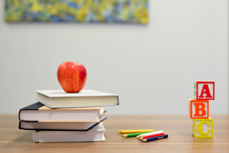 Stapel Schulbücher mit Apfel und Stifte