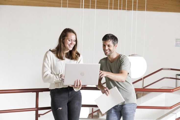 Kursteilnehmende diskutieren etwas am Laptop