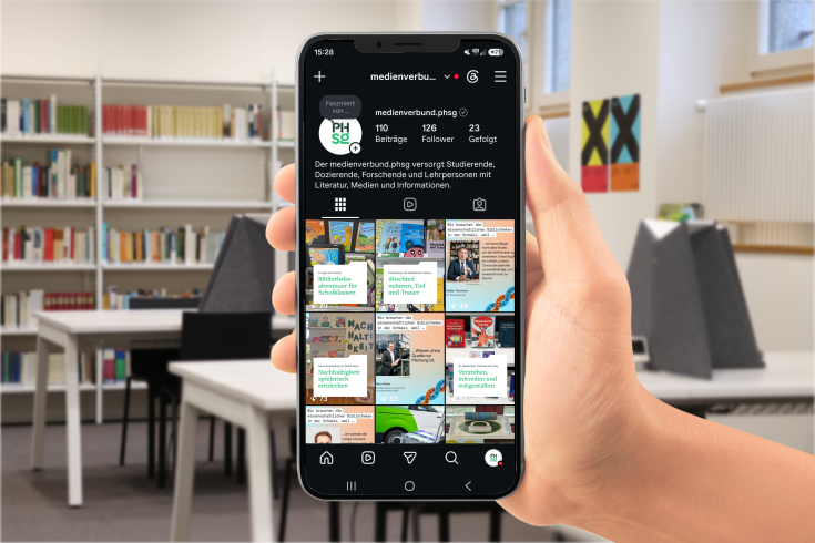 Ein Smartphone auf dem der Instagram-Account des medienverbund.phsg zu sehen ist, im Hintergrund sieht man die Bibliothek Hadwig