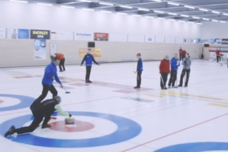 Mehrere Personen spielen Curling in einer Halle