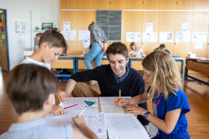 Fachperson ist mit Schülern um einen Tisch