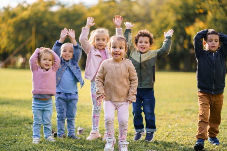 eine Gruppe Kinder bewegt die Arme im Freien